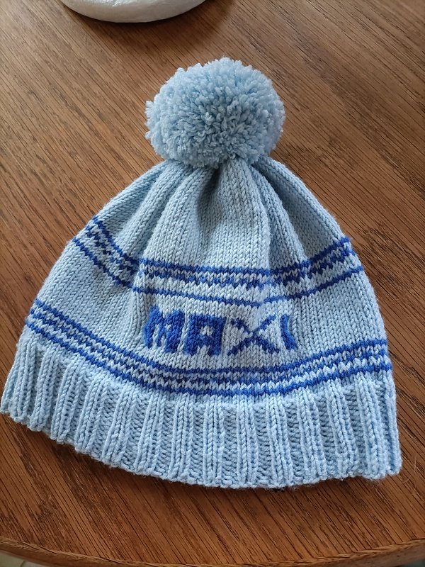 Hellblaue gestrickte Kindermütze mit dunkelblauen Streifen, Pompon und eingestricktem Schriftzug