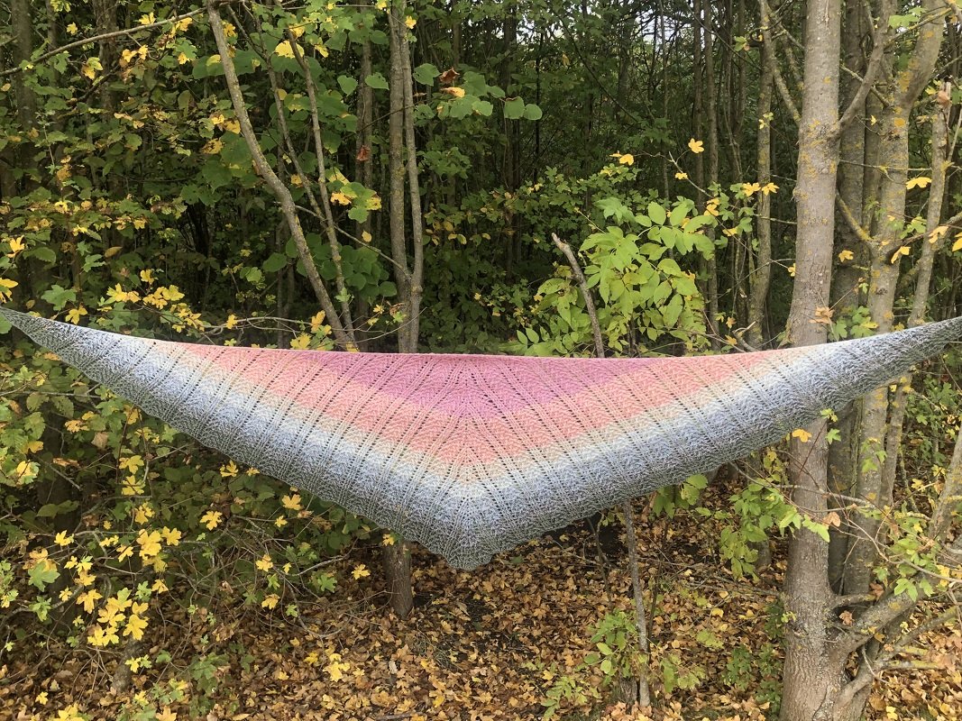 Gehäkeltes Dreieckstuch mit diagonalen Rippen und Farbverlauf, zwischen Bäumen gespannt