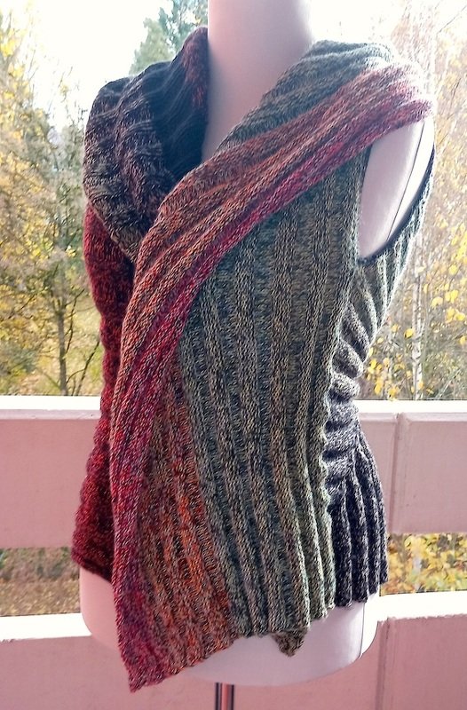 Ärmellose Strickweste mit vertikalem Rippenmuster und Farbverlauf in Grün, Orange und Rot auf Schaufensterpuppe.