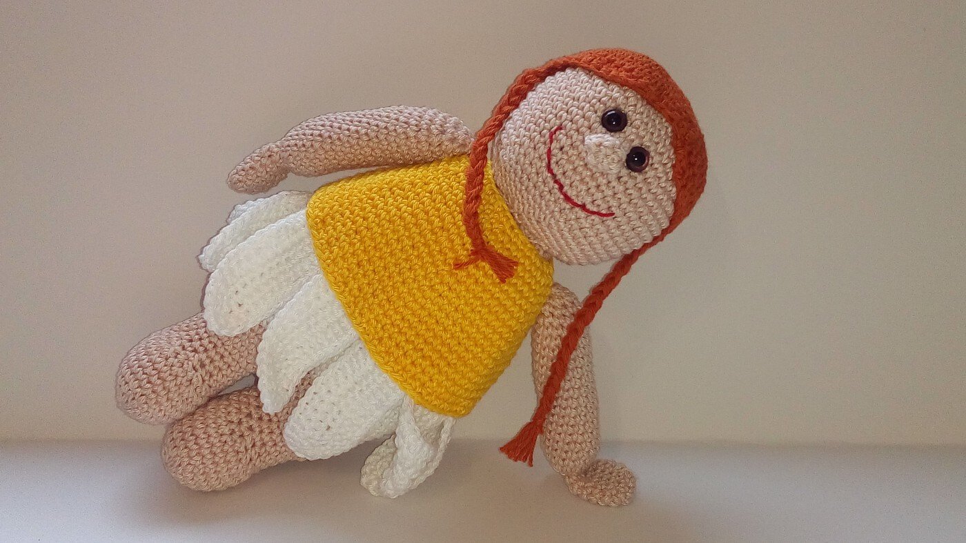 Gehäkelte Amigurumi-Puppe mit roten Zöpfen, gelbem Oberteil und weißem Blütenrock
