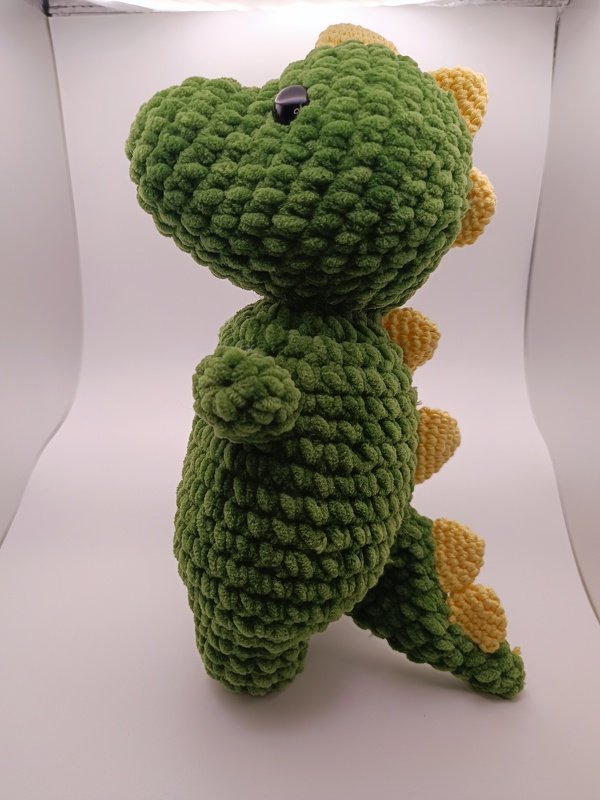 Seitenansicht: gehäkelter grüner Amigurumi-Dinosaurier mit gelben Zacken