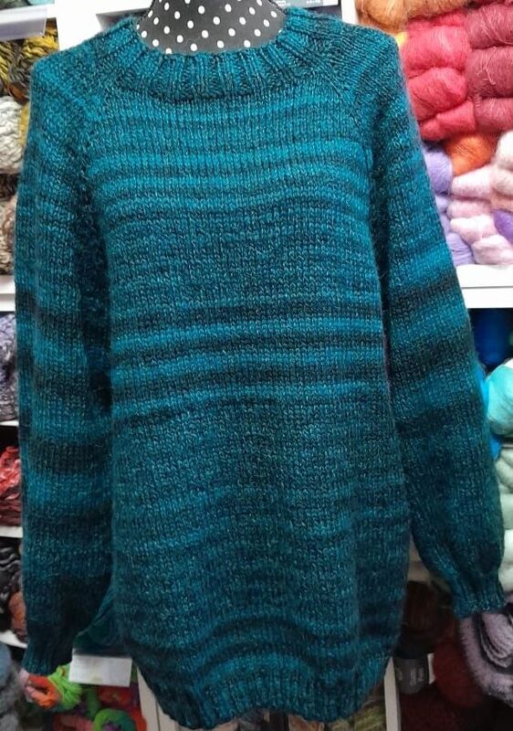 Gestrickter Herrenpullover in Petrolblau mit dunklen Streifen auf einer Schaufensterpuppe