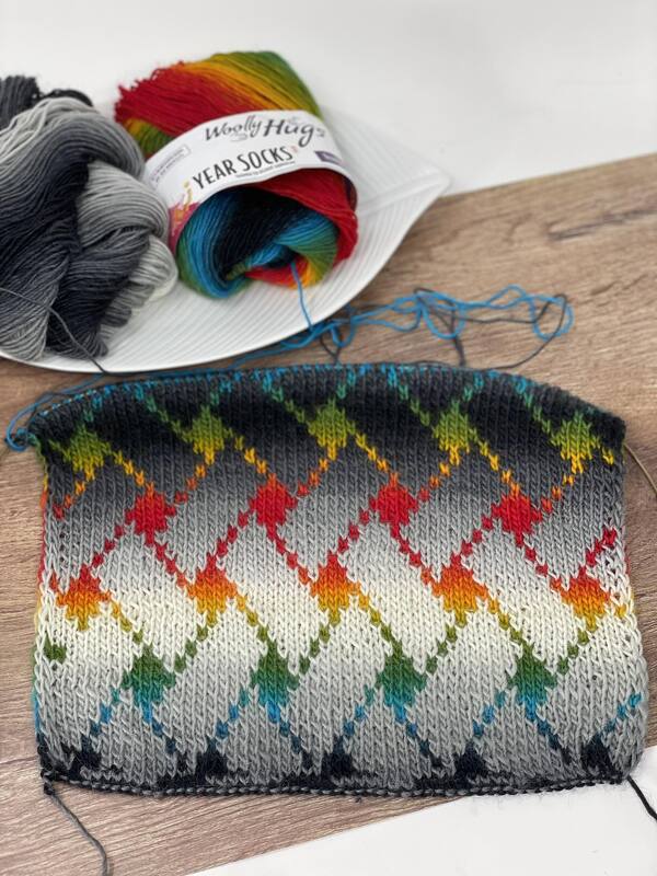 Gestrickter Schal mit bunten Rauten und Garnknäueln