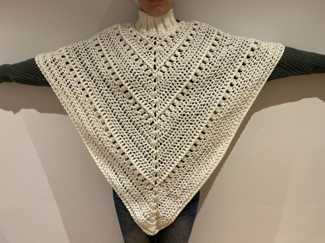 Cremefarbener handgehäkelter Dreieckponcho mit sichtbarer Mittelnaht und hohem Rollkragen