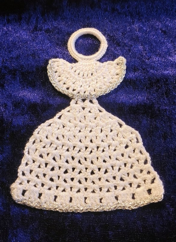 Weiß gehäkelter Engel mit silberner Borte auf dunkelblauem Stoff