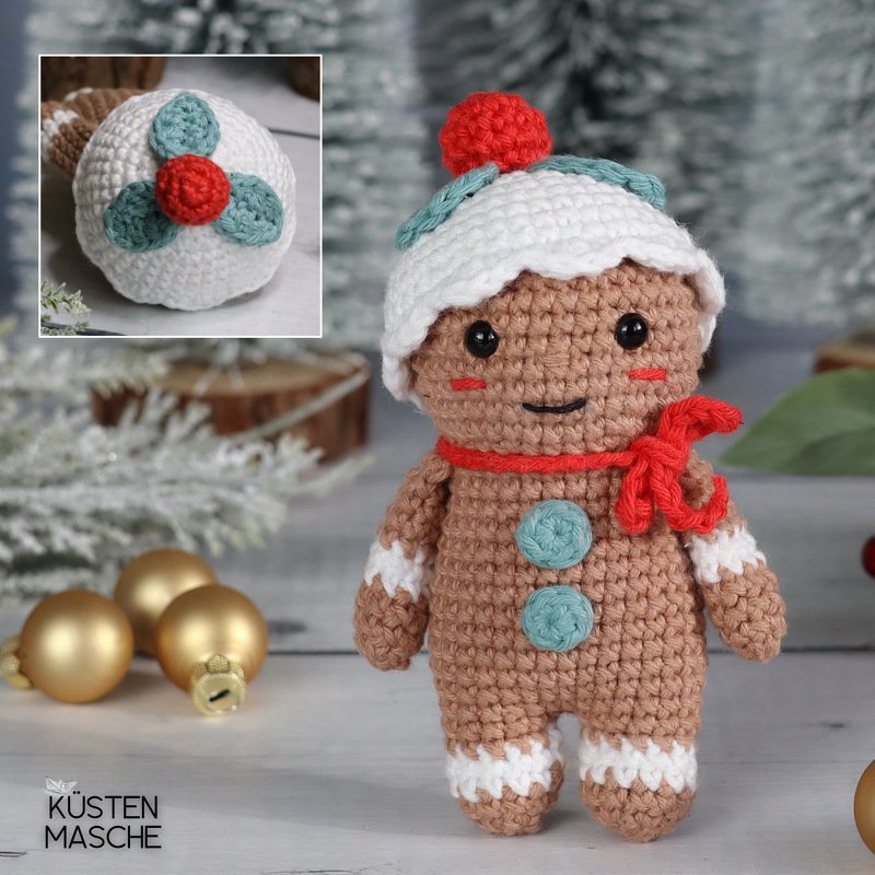 Gehäkelte Lebkuchen-Puppe mit weißer Mütze, rotem Schal und türkisfarbenen Knöpfen vor festlicher Kulisse