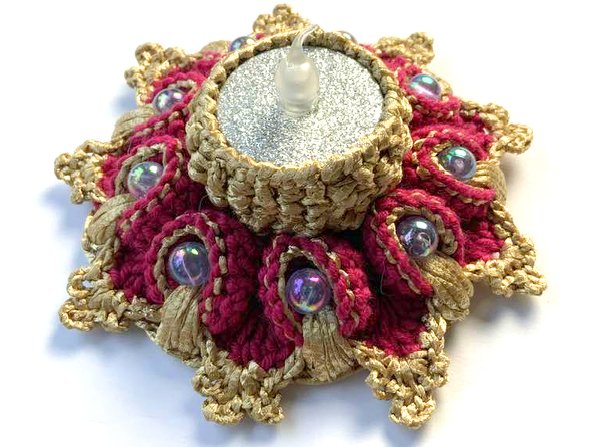 Gehäkelter sternförmiger Teelichthalter in Gold und Magenta mit Perlen und einer LED-Teelichtkerze
