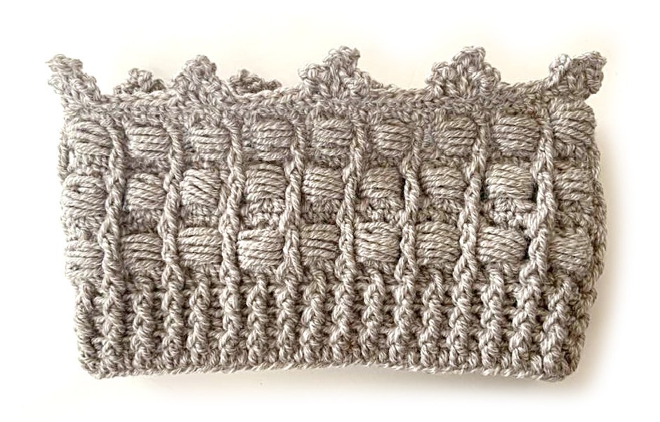 Gehäkeltes graues Stirnband mit Kronenrand auf weißem Hintergrund