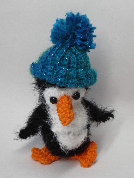 Gehäkelter Pinguin Amigurumi mit blauer Bommelmütze