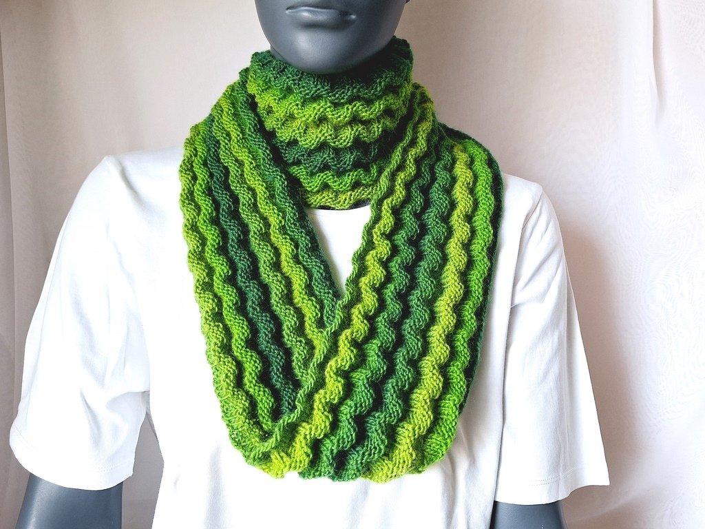 Gestrickter Loop‑Schal in Grüntönen mit Wellenmuster an Schaufensterpuppe