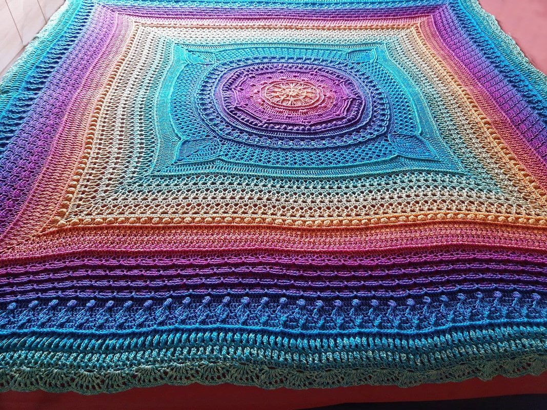 Quadratische Häkeldecke mit zentralem Mandala und Regenbogen-Farbverlauf
