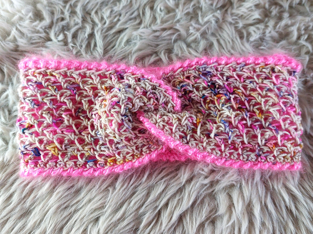 Kompaktes gehäkeltes Stirnband mit mittiger Drehung und pinker Umrandung