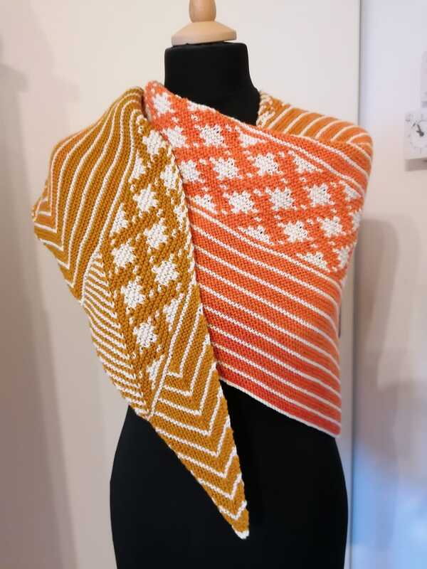 Gestricktes Dreieckstuch in Orange und Senfgelb mit weißen Mosaikmotiven und diagonalen Streifen auf Mannequin
