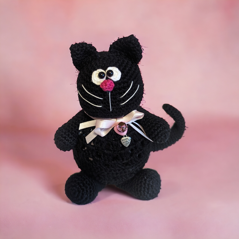 Handgehäkelte schwarze Katzen-Amigurumi mit rosa Schleife und Herzanhänger