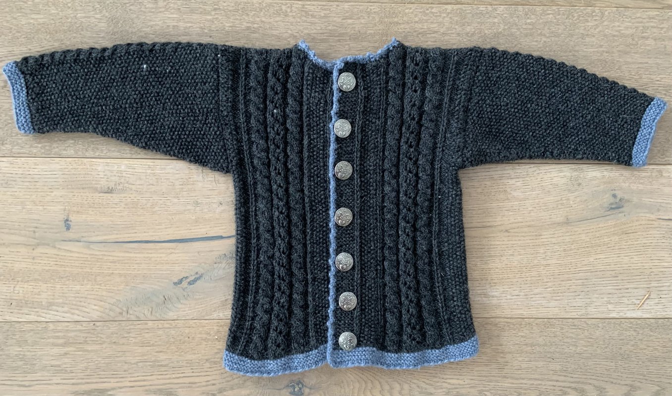 Dunkelgraue Kinderjacke mit Zopfmuster, sieben Metallknöpfen und hellblauer Einfassung