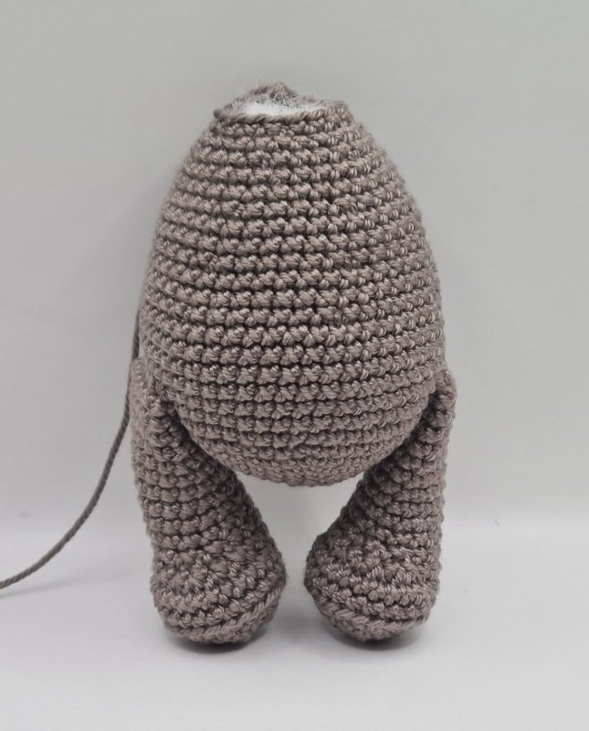 Gehäkelter Amigurumi-Rumpf mit zwei angenähten Beinen und sichtbarer Füllwatte