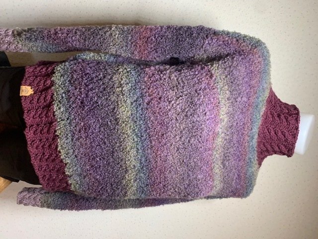 Flauschiger mehrfarbiger Damenpullover mit Streifen und Zopfmuster-Bündchen auf Schneiderbüste.