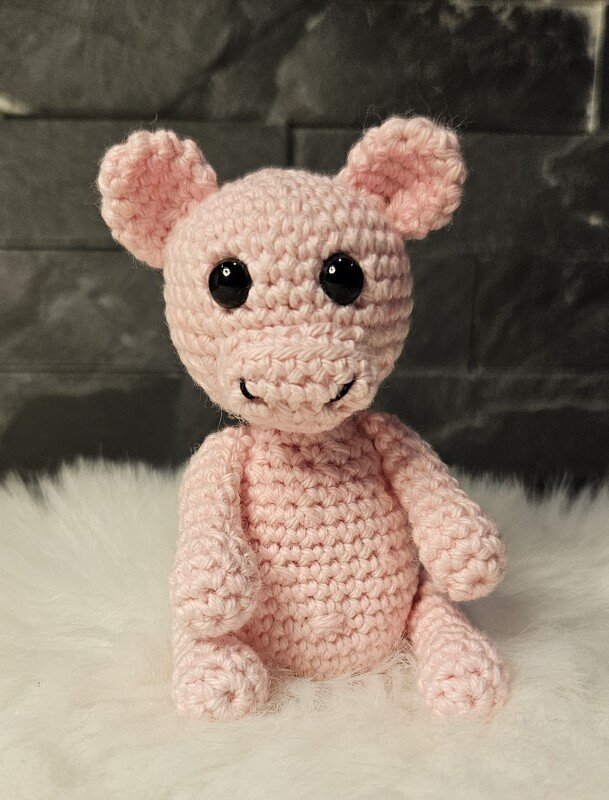 Nahaufnahme rosa Amigurumi zeigt Maschen, Arme und schwarze Sicherheitsaugen