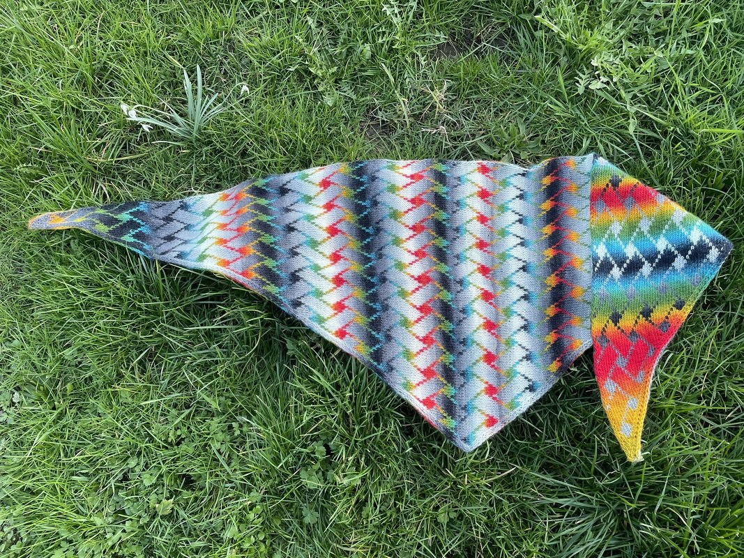 Mehrfarbiges gestricktes Dreieckstuch mit Zickzackmuster auf Gras