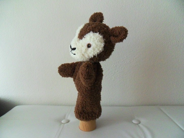 Gestrickte braun-weiße Reh-Handpuppe auf hellem Untergrund