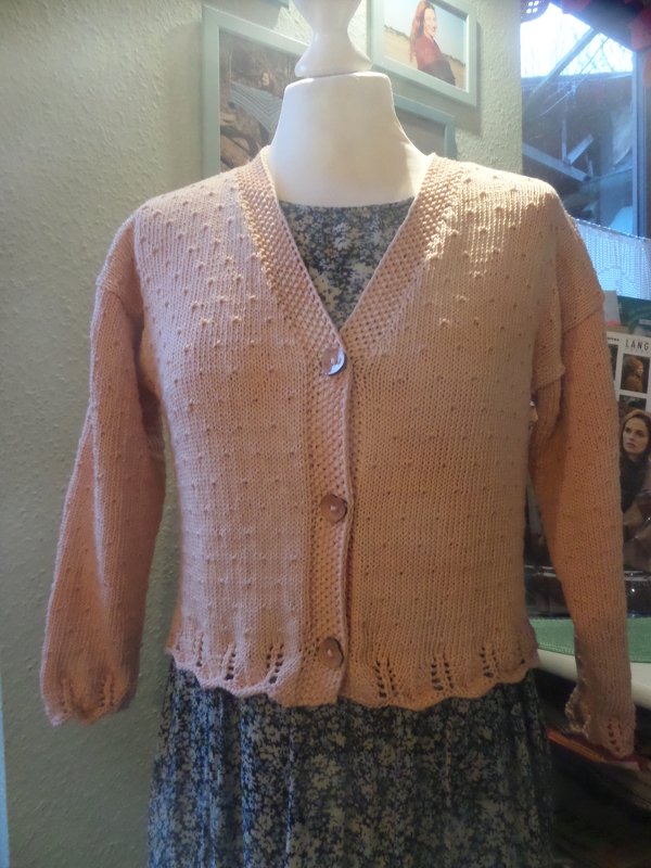 Pfirsichfarbene gestrickte Damenjacke mit V‑Ausschnitt und Knöpfen auf Büste