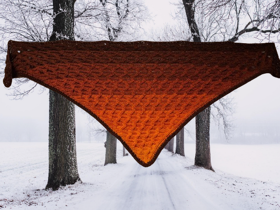 Gehäkeltes Dreieckstuch in Orange-Braun mit Strukturmuster, aufgehängt vor verschneiter Baumallee