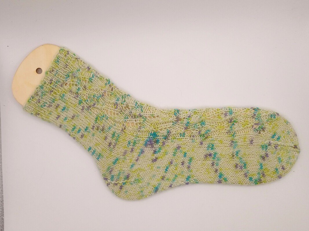 Gestrickte Socke mit gesprenkeltem Garn und Lochmuster auf Holzsockenblocker