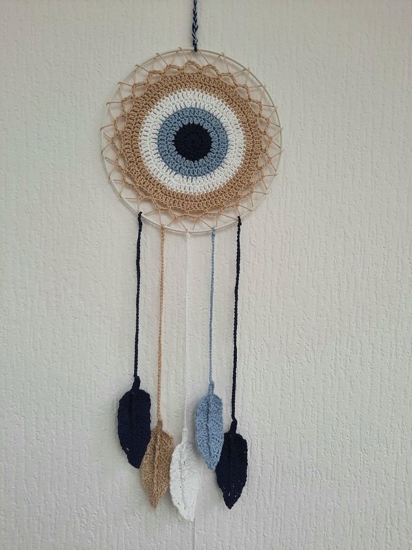Gehäkelter Wandbehang mit Nazar-Auge in Blau, Beige und Weiß und fünf herabhängenden Häkelblättern