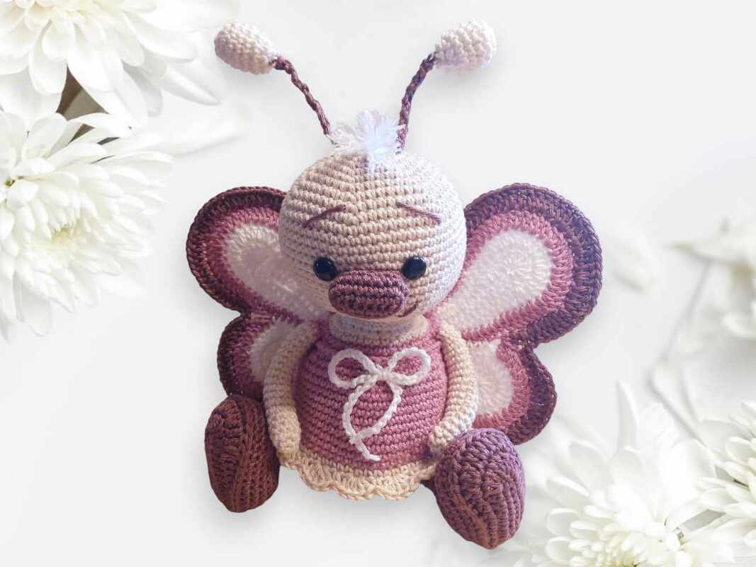 Handgehäkeltes Schmetterlings-Amigurumi mit abgesetzten Flügelrändern und Schleifen-Detail
