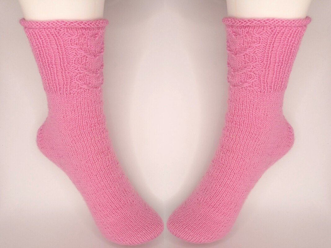 Paar rosa gestrickter Socken mit Zopfmuster am Schaft