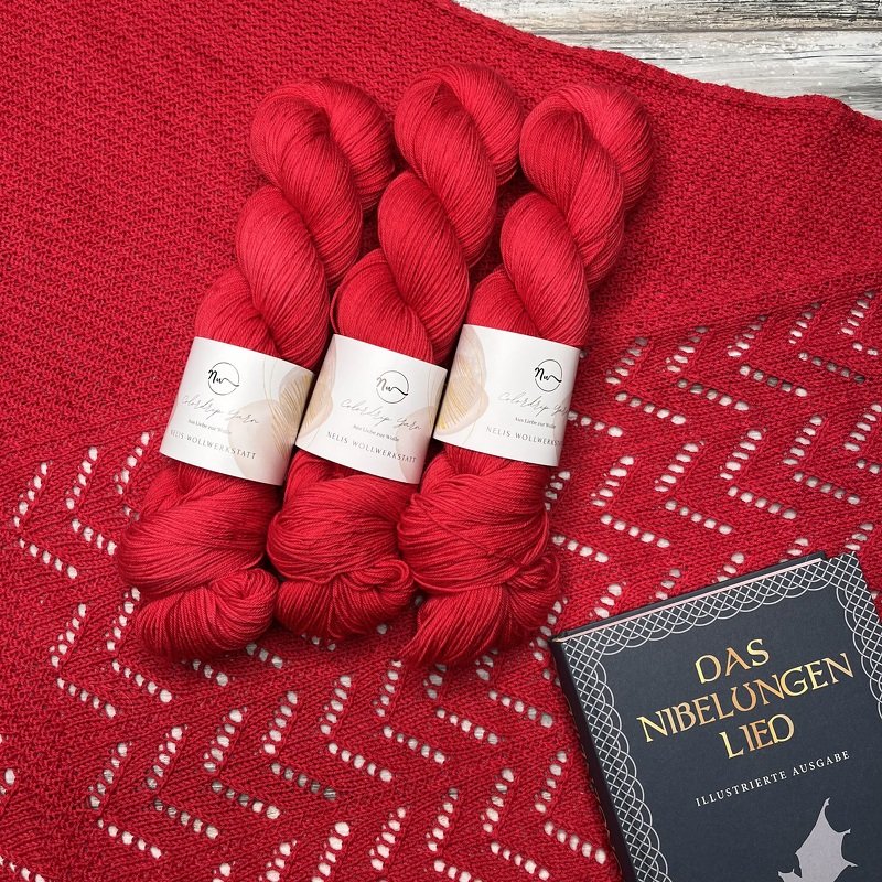 Rotes Dreieckstuch mit Zickzack-Lacemuster und drei roten Garnsträngen