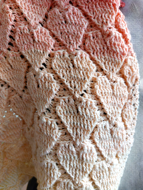 Macro photo of heart lace stitch pattern on a crochet loop scarf in peach yarn
