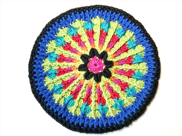 Rundes Häkeldeckchen in leuchtenden Farben auf weißem Hintergrund