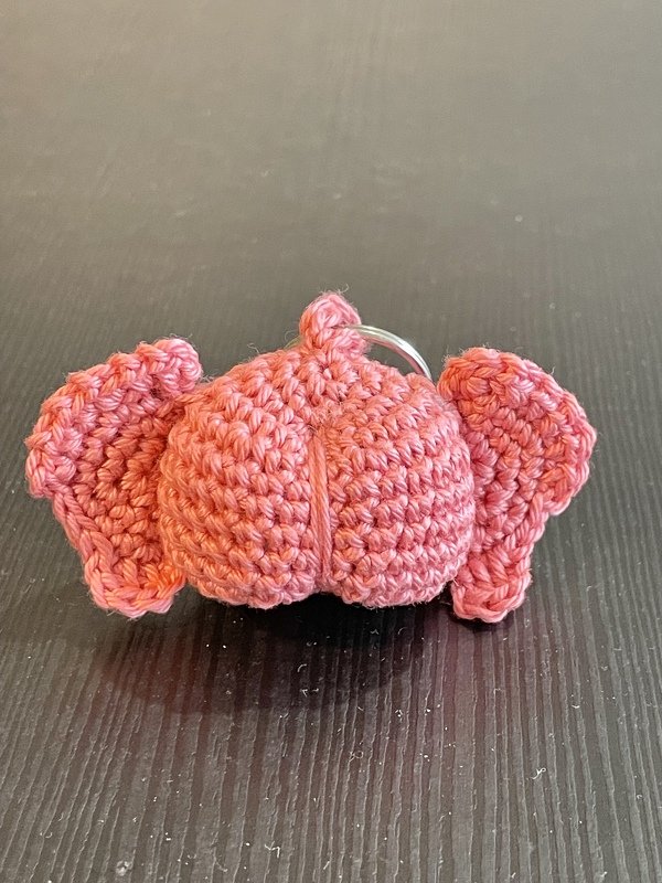 Rosa gehäkelter Elefantenschlüsselanhänger mit Metallring auf dunklem Tisch