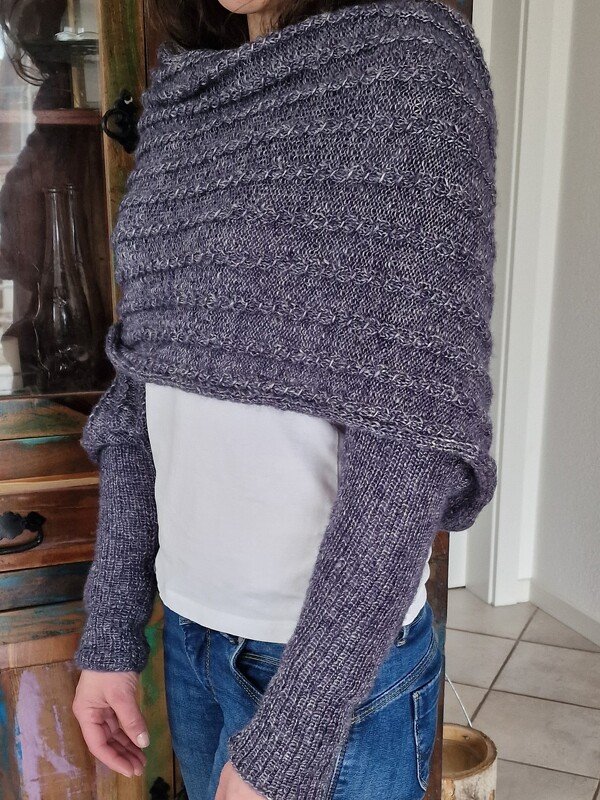 Gestrickter Shrug in Grau-Lila Melange mit Strukturmuster und langen Ärmeln, getragen