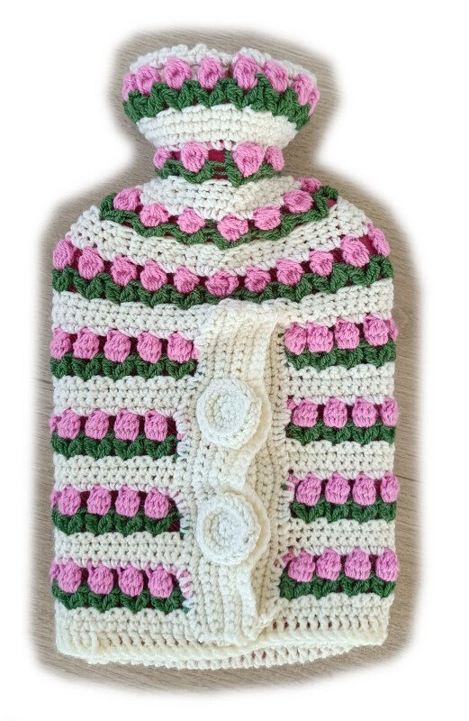 Gehäkelter Wärmflaschenbezug cremeweiß mit rosa Noppen, grünen Streifen und zwei Knöpfen