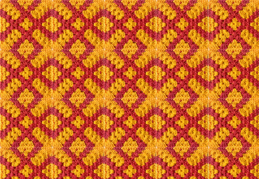 Wiederholendes gehäkeltes Granny-Square-Muster in Rot und Gelb mit diagonalen Rhomben
