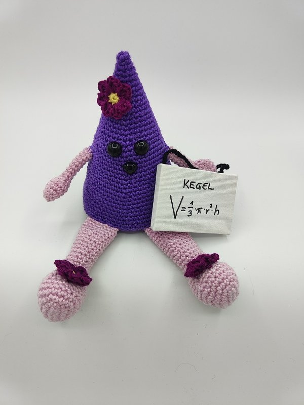Lila gehäkelter Kegel-Amigurumi mit rosafarbenen Gliedmaßen, Blume am Kopf und Schild mit der Volumenformel V = 1/377r27h.
