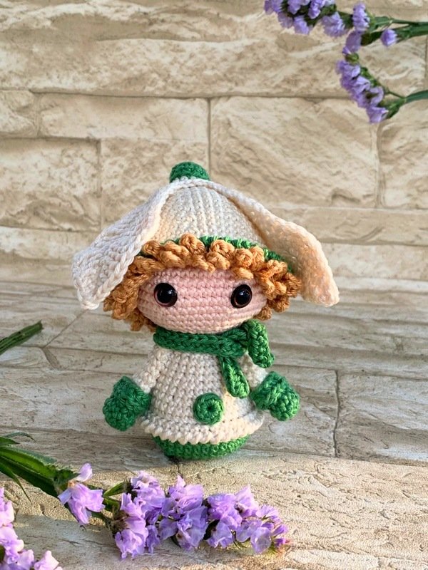Gehäkelte Amigurumi-Puppe mit weißer Blütenmütze und grünen Details