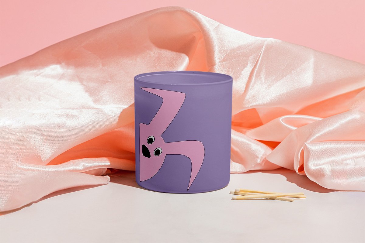 Lila zylindrischer Behälter mit rosa Hasenmotiv, daneben Zündhölzer; rosafarbener Seidenstoff im Hintergrund.