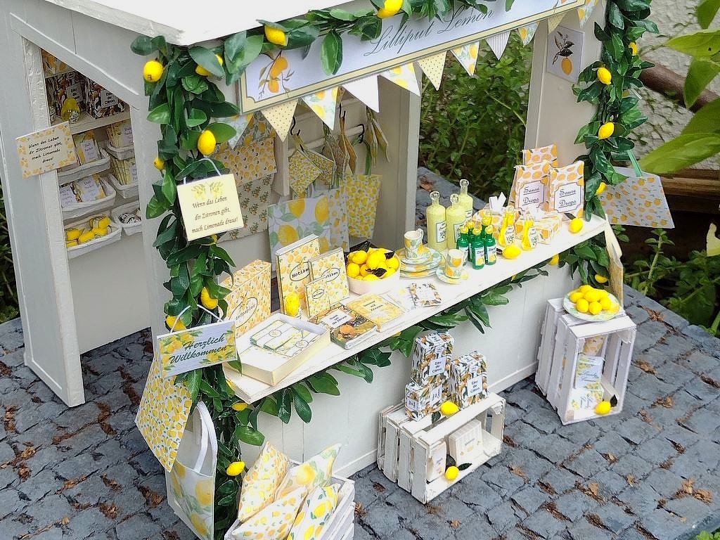 Bastelstand in Miniatur mit Zitronenmuster, Papiertüten und weißen Miniaturkisten