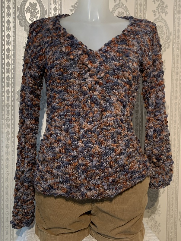 Gestrickter Damenpullover mit V-Ausschnitt in melierten Blau- und Brauntönen auf Schaufensterpuppe