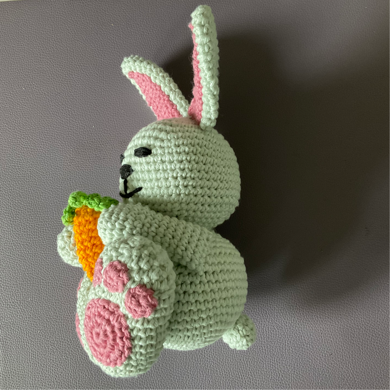 Gehäkelter mintgrüner Hase mit rosa Details und orangefarbener Karotte