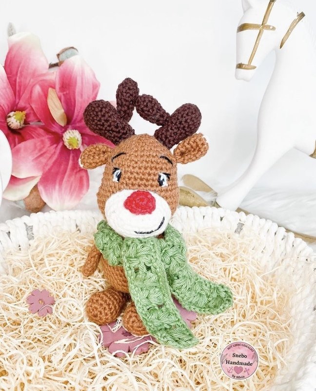 Braunes Rentier-Amigurumi gehäkelt mit roter Nase und grünem Schal