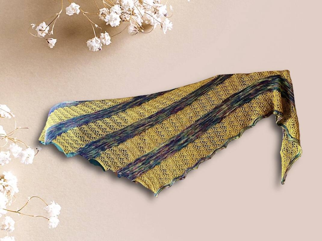 Gestricktes dreieckiges Tuch gelb mit schmalen mehrfarbigen Streifen, Lochmuster und gezacktem Rand auf beigem Hintergrund