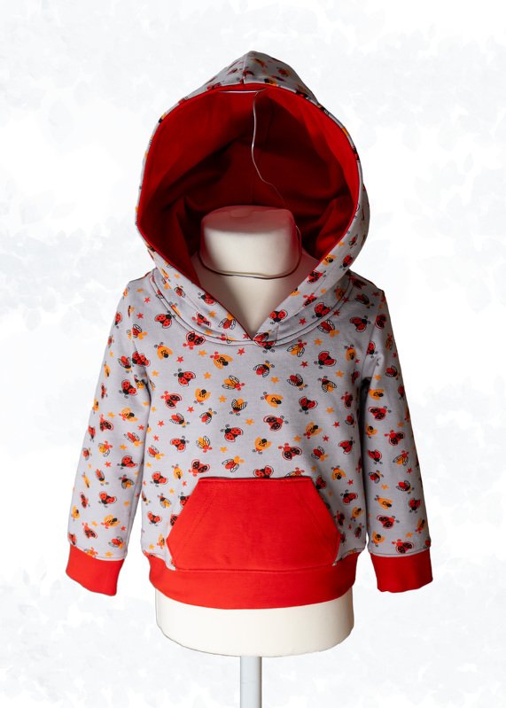 Hellgrauer Kinder-Hoodie mit roter Kapuze und Kängurutasche, bedruckt mit Marienkäfern, Bienen und Sternen auf einer Schaufensterpuppe.