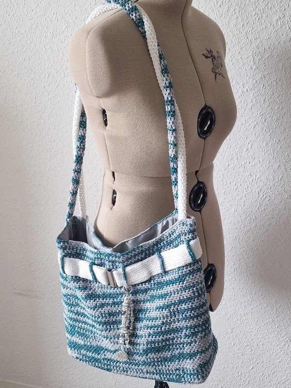 Gehäkelte türkis-weiße Shopper-Tasche mit langem Träger an einer Schneiderpuppe