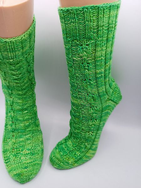 Wadenlange grüne gestrickte Socken mit Zopfmuster auf Schaufensterbeinen, Vorder- und Seitenansicht