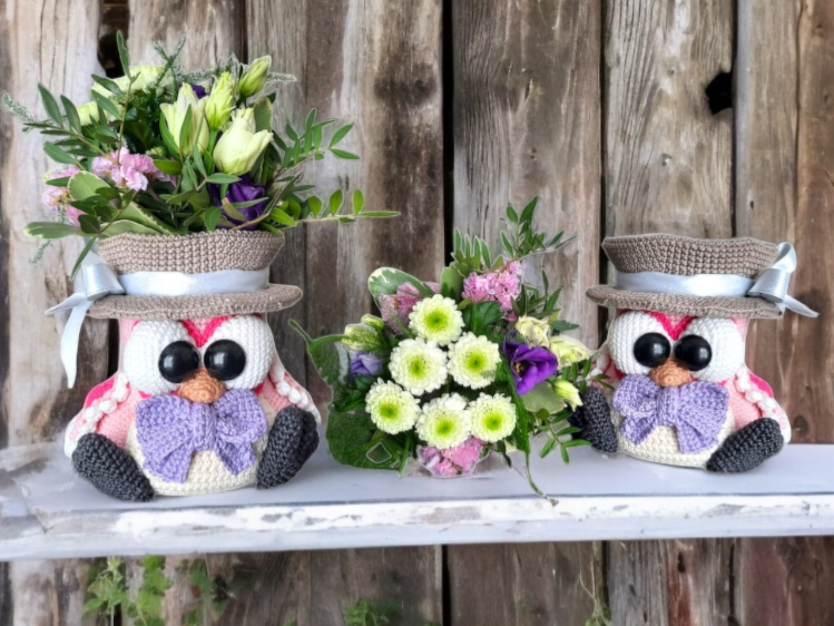 Pair of crocheted owl flower holders with ribbon hats arranged as a table centerpiece