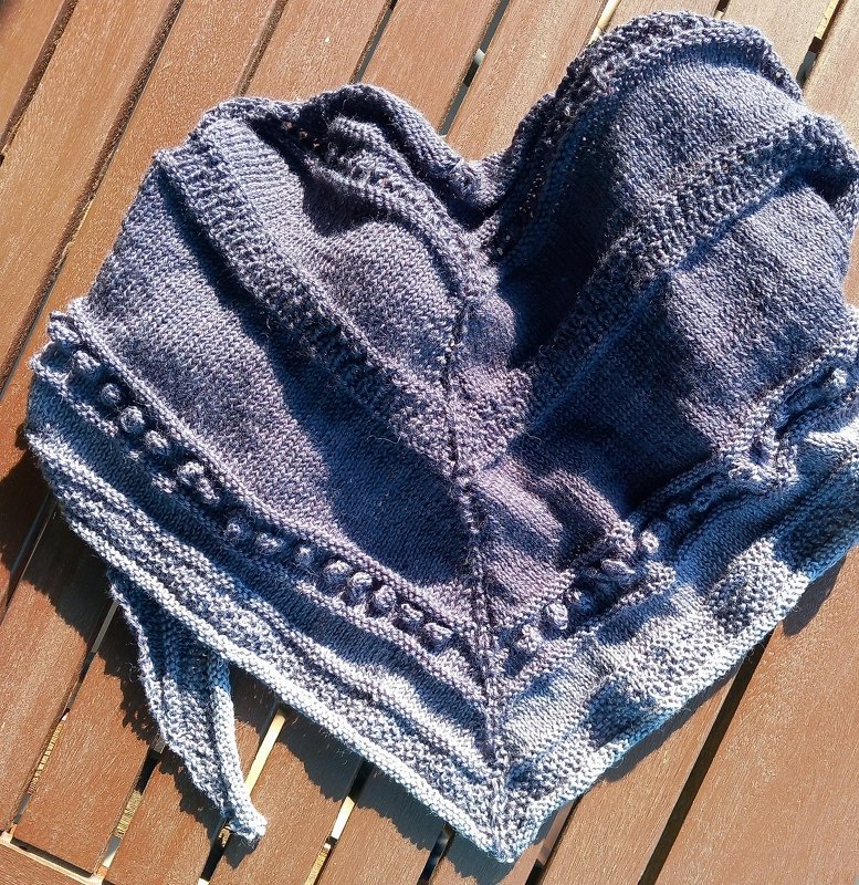 Gestricktes Dreieckstuch mit Noppenreihen und krausrechts gestricktem Rand, grau‑blauer Verlauf, auf Holztisch ausgelegt